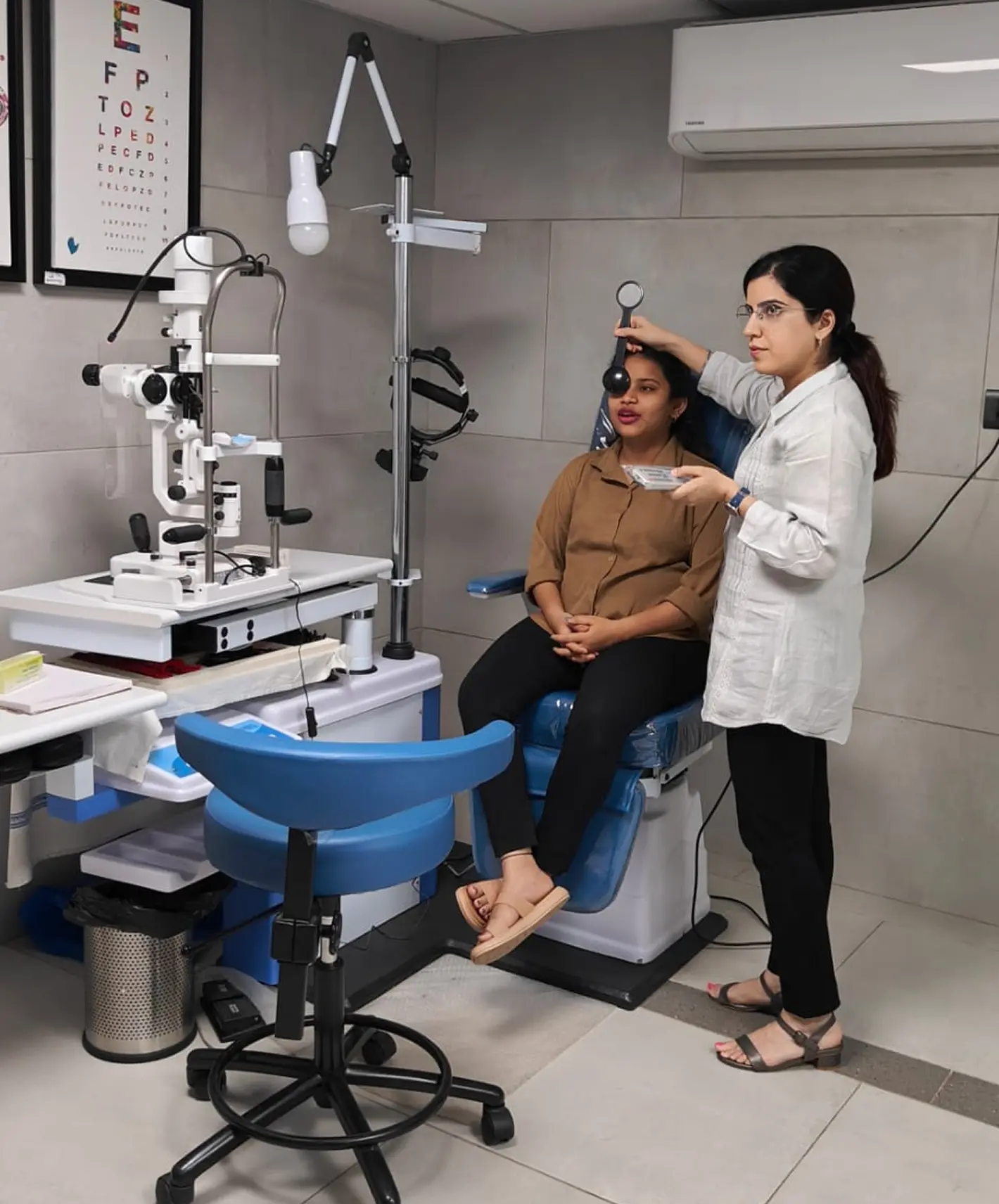 Dr. Sahiba Bedi conducting an eye test on a patient using specialized optical equipment in a clean, modern ophthalmology clinic