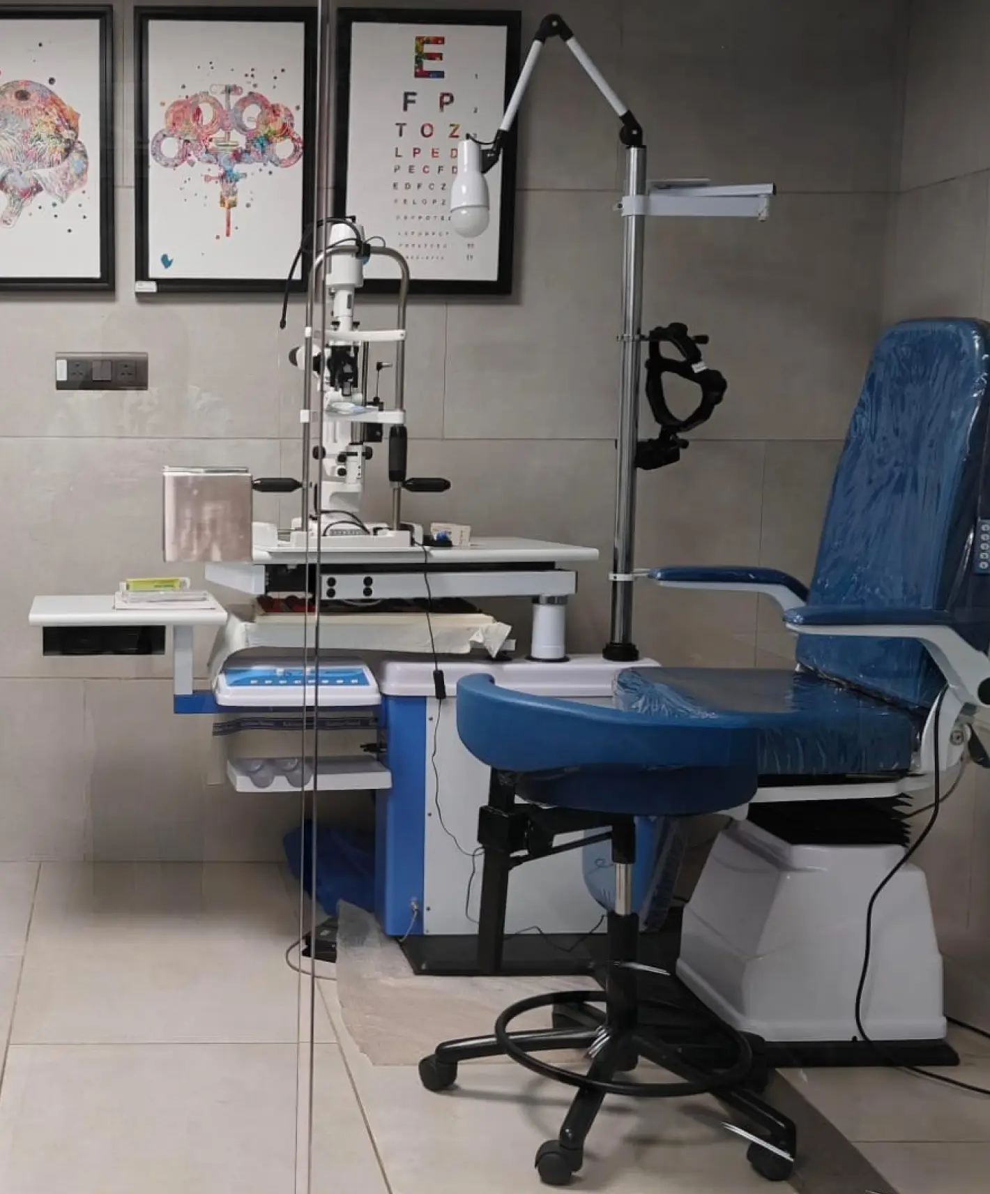 Ophthalmology clinic setup with a slit lamp microscope, eye exam chair, and test charts on the wall, showing a well-equipped space for eye care consultations